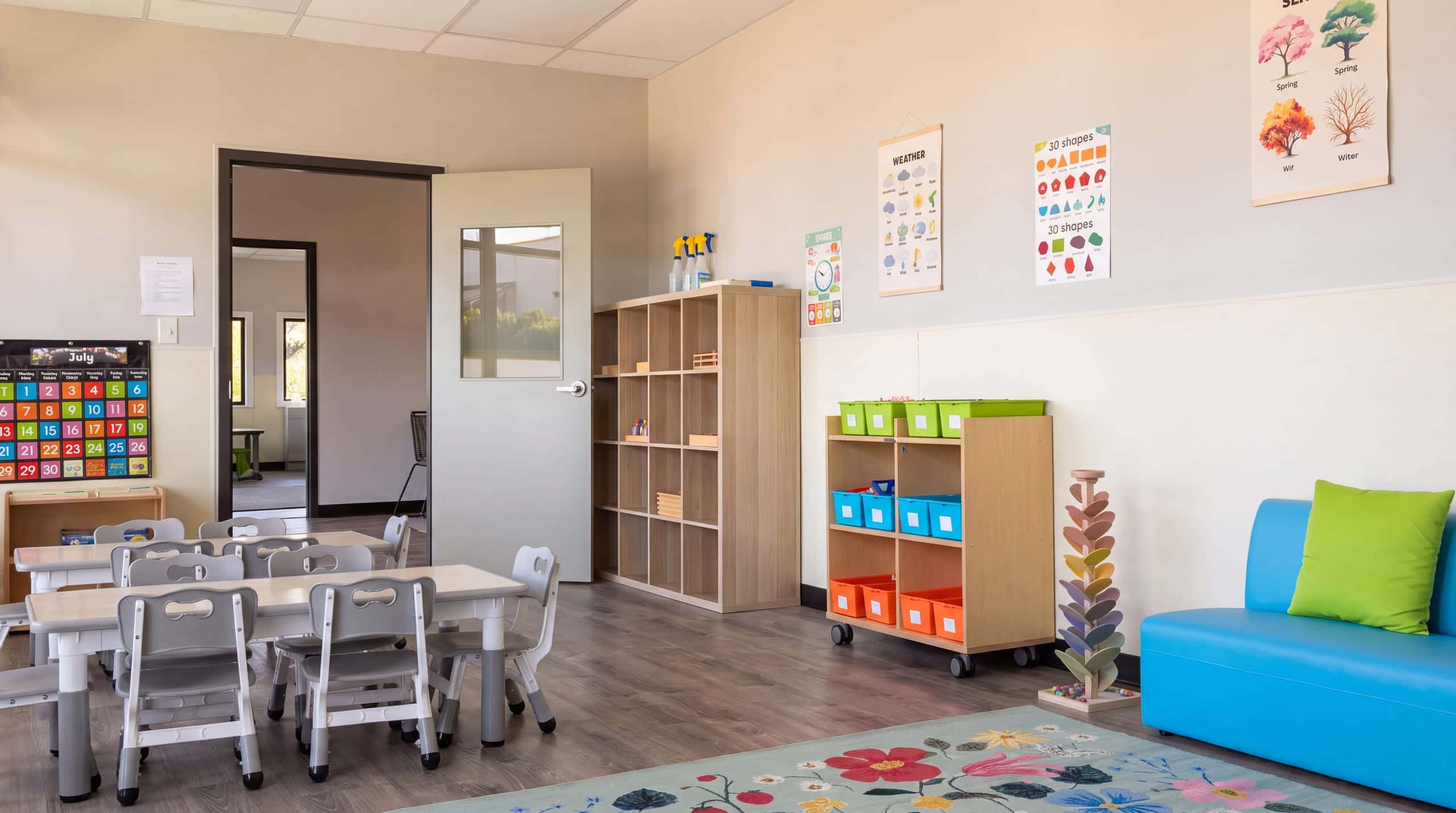 A classroom tidy and ready for an afternoon tour, the door open to the next room