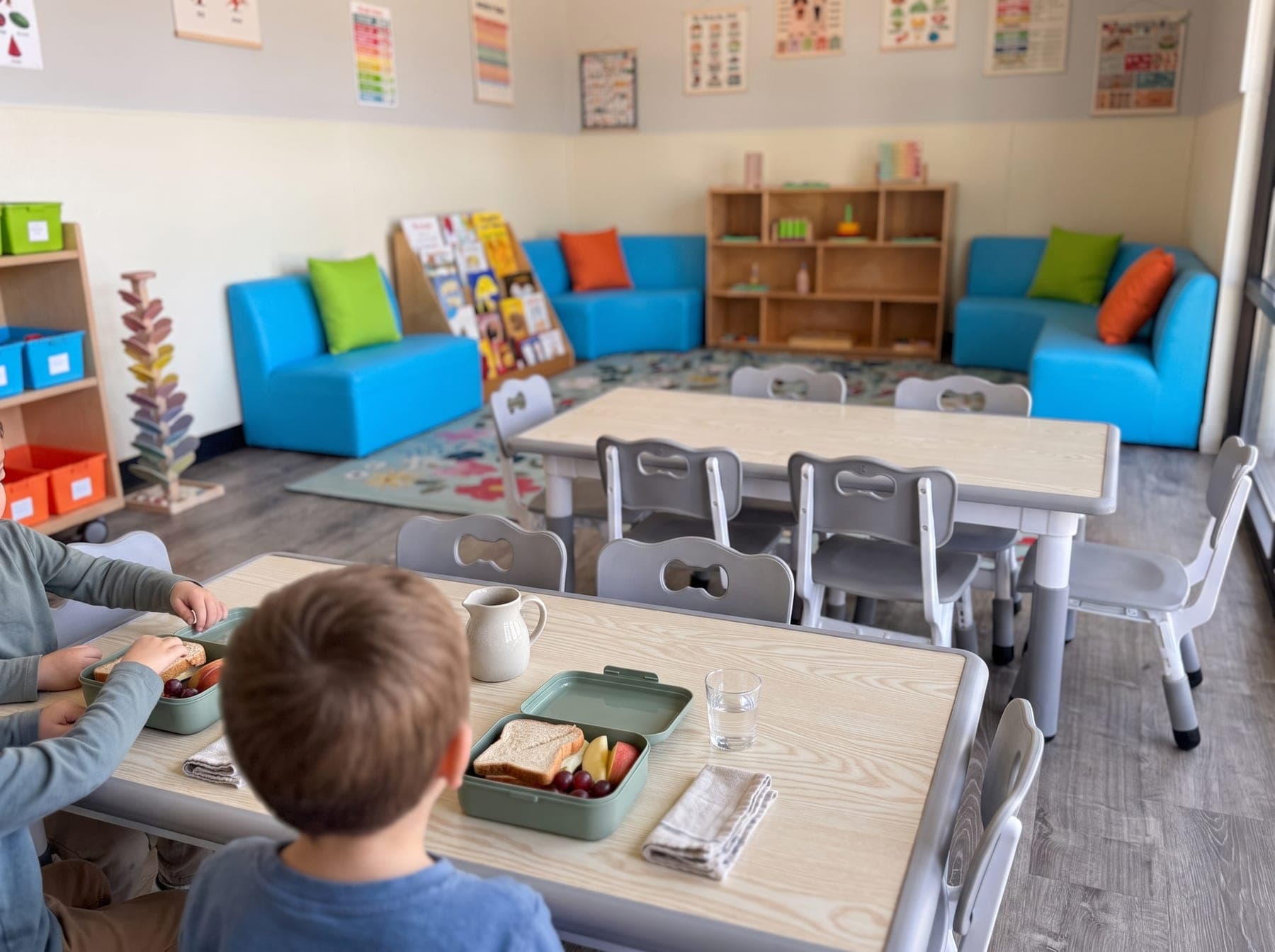 Children's hands at lunch: a lunchbox, fruit and a real glass of water on a child-sized table