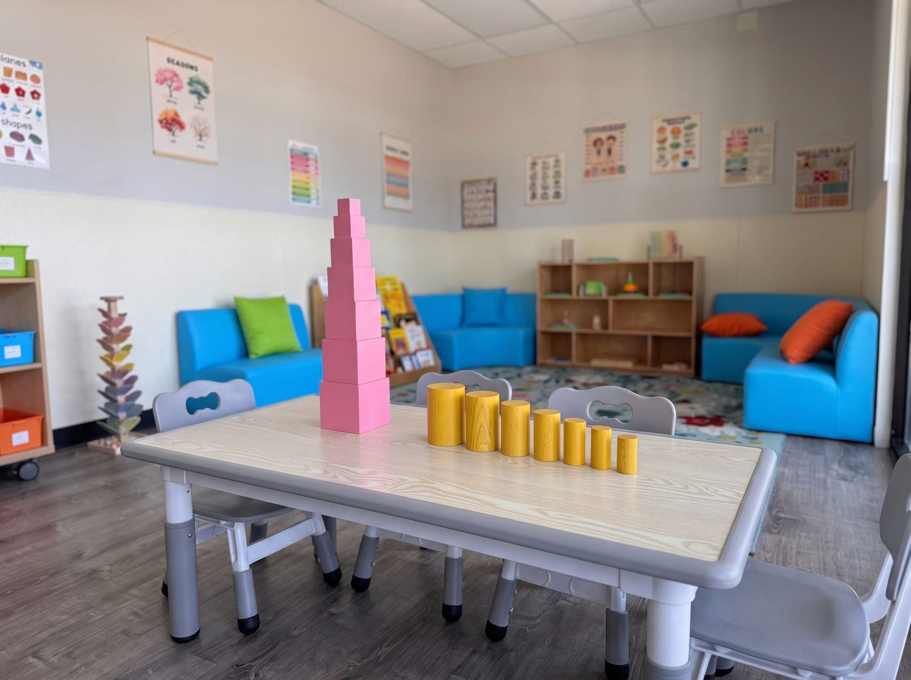 Pink tower cubes and a row of knobless cylinders arranged on a light-ash tabletop